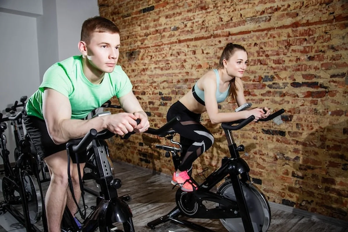 Młody mężczyzna i kobieta ćwiczą na rowerach w siłowni
