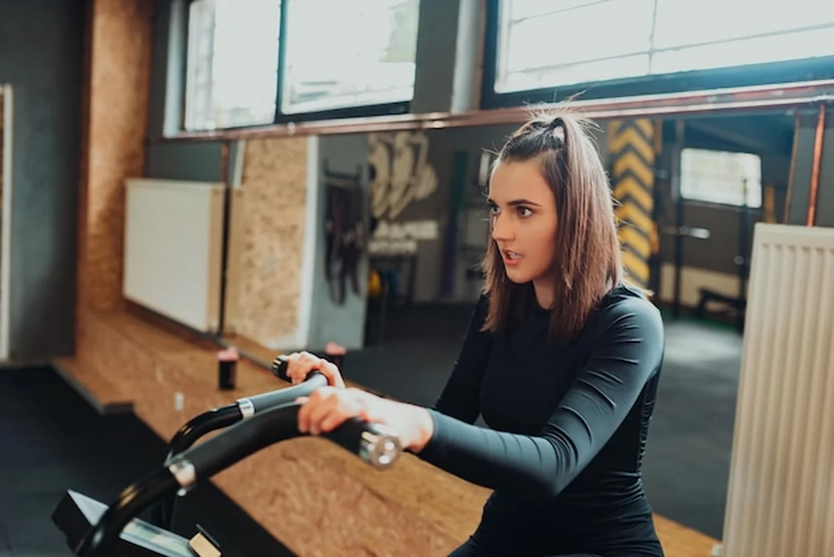 Kaukaska kobieta w odzieży sportowej na rowerze treningowym