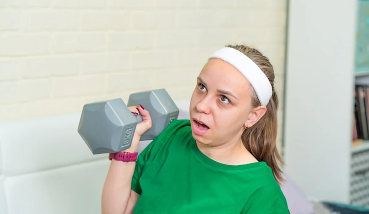 Młoda kobieta ćwiczy z halterem w studiu fitness podczas treningu siłowego