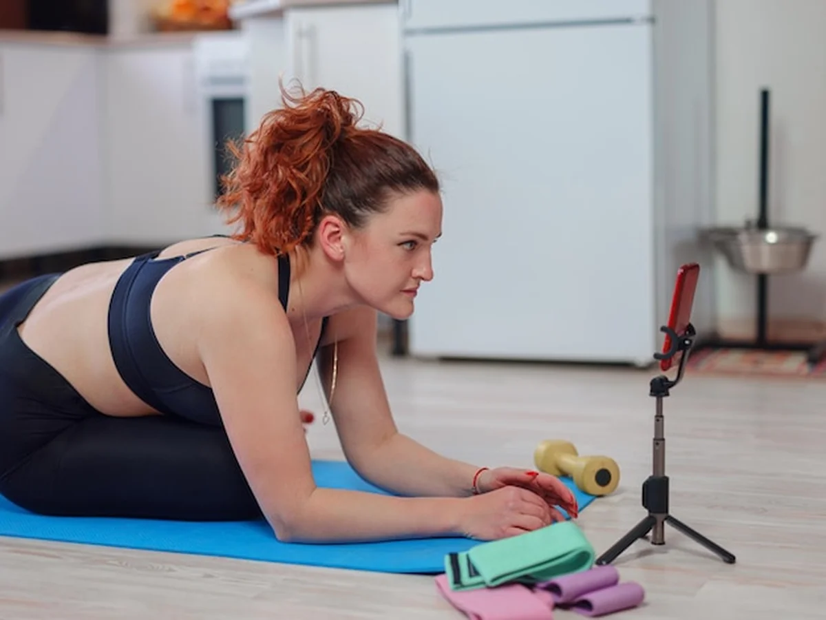 Młoda kobieta ćwicząca w domu przy smartfonie