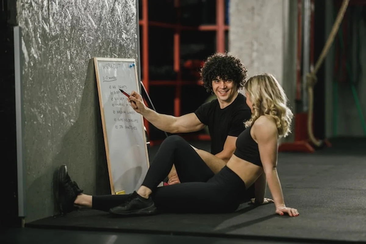 Kobieta i trener na siłowni ćwiczący plan treningowy