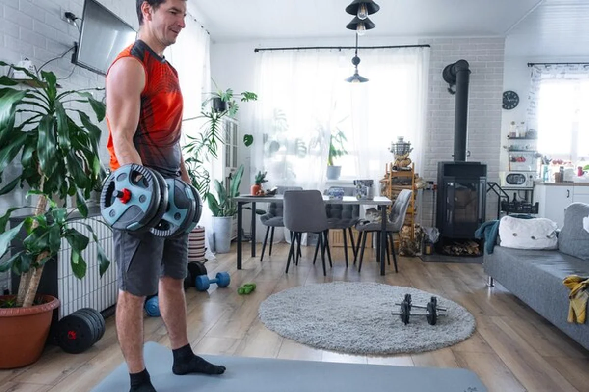 Trening siłowy mężczyzny w domu z hantlami ćwiczenie bicepsów z dużym obciążeniem
