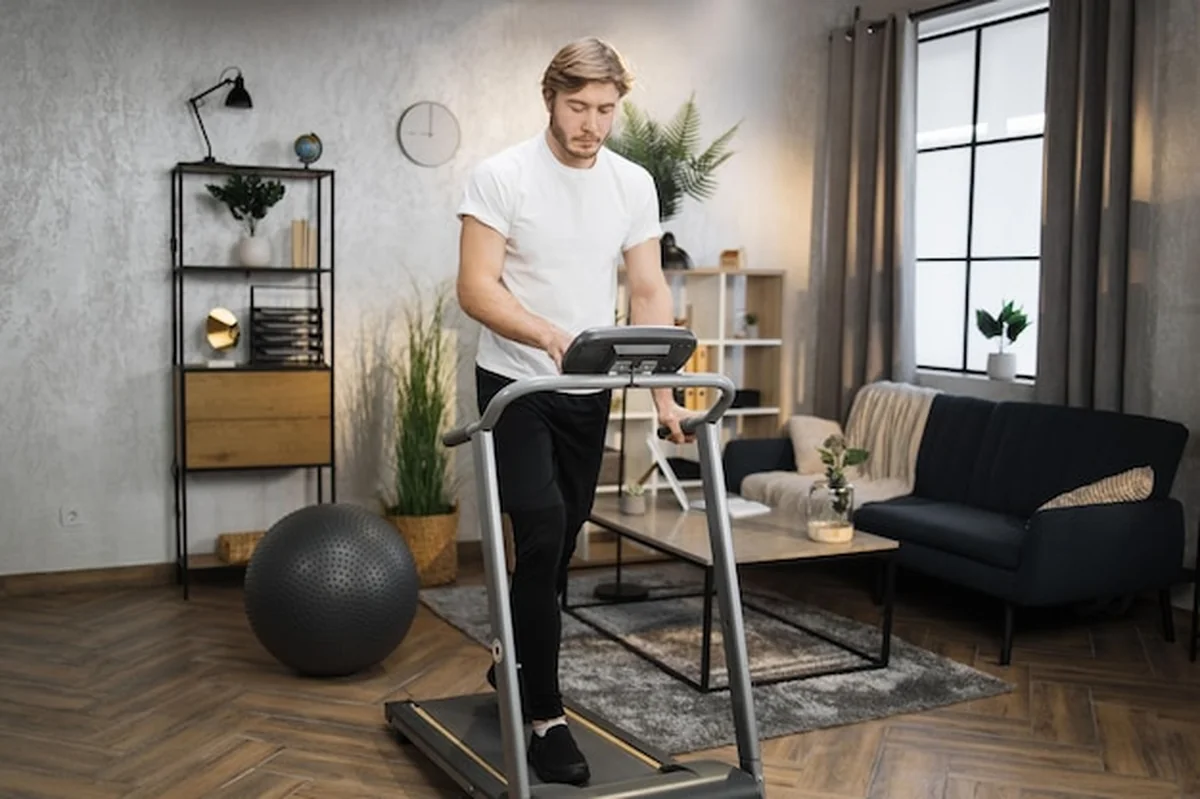 Młody sportowiec na bieżni w domowej siłowni