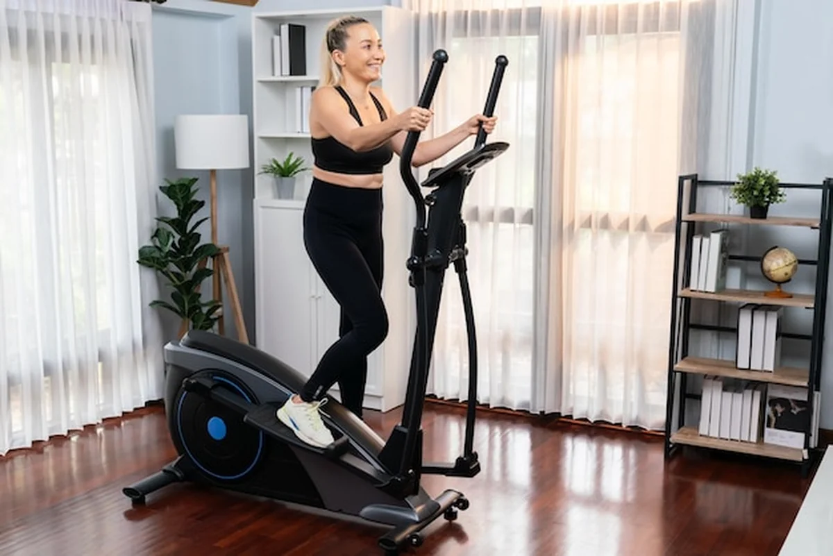 Starsza kobieta biegająca na bieżni eliptycznej w domu